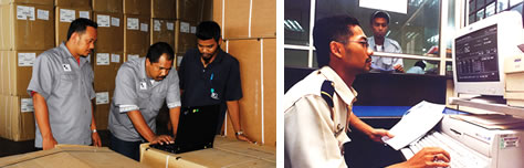 ILS forwarding staff reviewing customs documentation at a laptop and at a clearance terminal