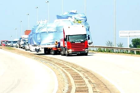 An oversized wrapped cargo on a prime mover leading a road convoy